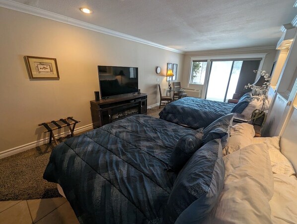A bedroom with a bed, a TV, a lamp, and a window.