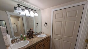 Une salle de bain avec deux lavabos, un miroir et une porte.