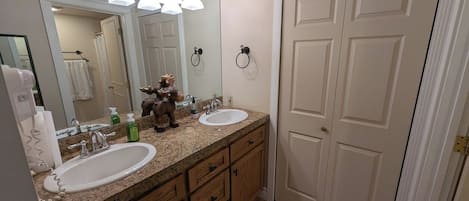 Une salle de bain avec deux lavabos, un miroir et une porte.