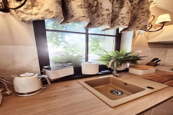 Una cocina moderna con un lavamanos, un hervidor y una ventana con vistas a la vegetación.