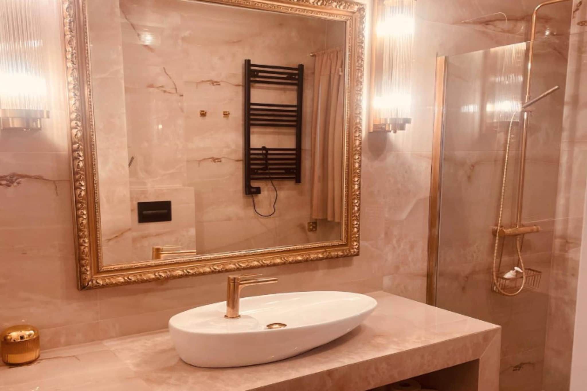 A bathroom with a large mirror, a white sink, a towel rack, and a shower.