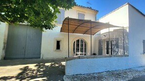 A white building with a covered patio, a garage, and a small window.