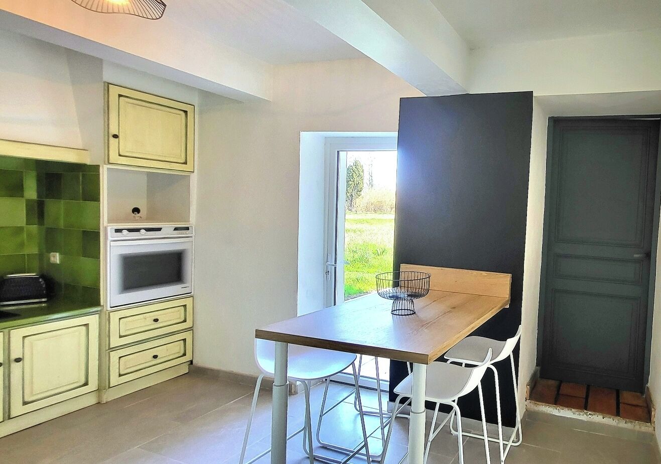 A compact kitchen with a dining area, a window, and a door.