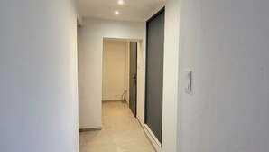 A narrow hallway with a sliding door on the right, a light switch on the wall, and a tiled floor.