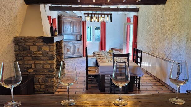 A rustic dining area with a stone fireplace, wooden table, and chairs.