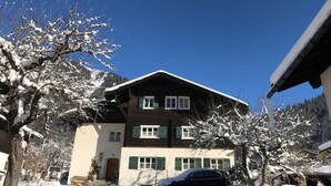 A two-story chalet with a sloped roof, wooden exterior, and green shutters. - Apartment in Gaschurn for 4 People (Gaschurn)