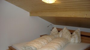 A single bed with a wooden headboard and a slanted ceiling. - Apartment in Gaschurn for 4 People (Gaschurn)