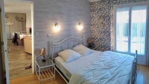 Een slaapkamer met een bed, nachtkastjes en een raam met gordijnen.