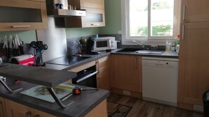 Een keuken met houten kastjes, een magnetron, een spoelbak en een vaatwasser.