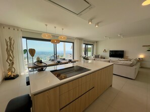 A modern kitchen with a central island, large windows, and a view of the landscape. - OneHeights: A luxuriously furnished apartment in a prime location with a phenomenal view! (La Cala de Mijas)