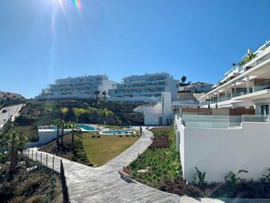 A modern residential area with a pool, a clear sky, and a view of multi-story buildings. - OneHeights: A luxuriously furnished apartment in a prime location with a phenomenal view! (La Cala de Mijas)