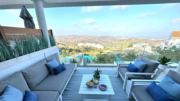 Un espace extérieur moderne, aménagé pour se détendre, avec vue sur un paysage côtier.