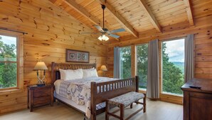 Un dormitorio de cabaña de madera con cama, banco, mesitas de noche y escritorio.