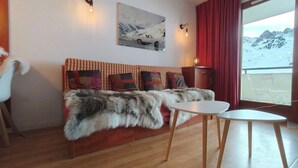 A cozy room with a fur-covered sofa, a small round table, and a painting of a car on the wall. - T2 swimming pool, terrace, private parking R. Pic du Midi (Bagnères-de-Bigorre)