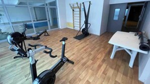 A gym with exercise equipment, a wooden floor, and a white table. - T2 swimming pool, terrace, private parking R. Pic du Midi (Bagnères-de-Bigorre)