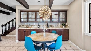 Een keuken met een ronde tafel, blauwe stoelen en een sierlijke kroonluchter.