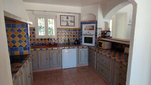 Une cuisine avec des carreaux bleus et jaunes formant un motif, un four encastré, un four à micro-ondes et un évier.