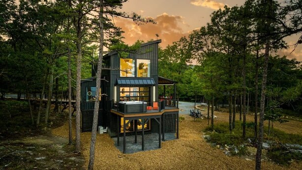 A modern cabin with a glass facade, surrounded by trees. - Monte Vista~Golf~Views~PS5~Sport Court~EV Charger (Berkeley Springs)