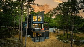A modern cabin with a glass facade, surrounded by trees.