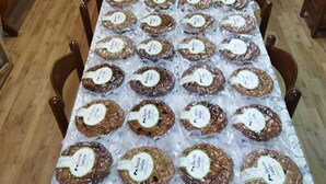 Uma mesa comprida coberta com produtos alimentícios embalados, provavelmente para venda ou exposição.