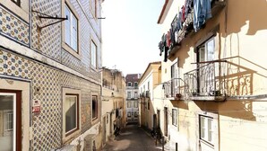 Una calle estrecha flanqueada por edificios con fachadas de azulejos y balcones con ropa tendida.