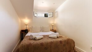 Un dormitorio pequeño y acogedor con una cama individual, dos lámparas de noche y un ventanal.