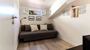 Una sala de estar moderna con un sofá gris oscuro, piso de madera y un televisor montado en la pared.