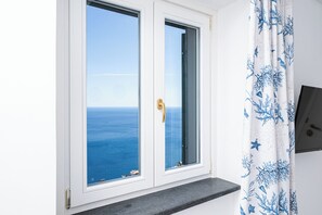 Enjoy a stunning sea view from the large window, framed in white with a golden handle.