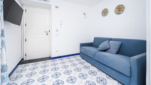 A room with a blue sofa, a white door, and patterned floor tiles. - Van Gogh Room (Amalfi)