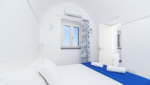 A bedroom with a bed, a window, and an air conditioning unit. - Van Gogh Room (Amalfi)