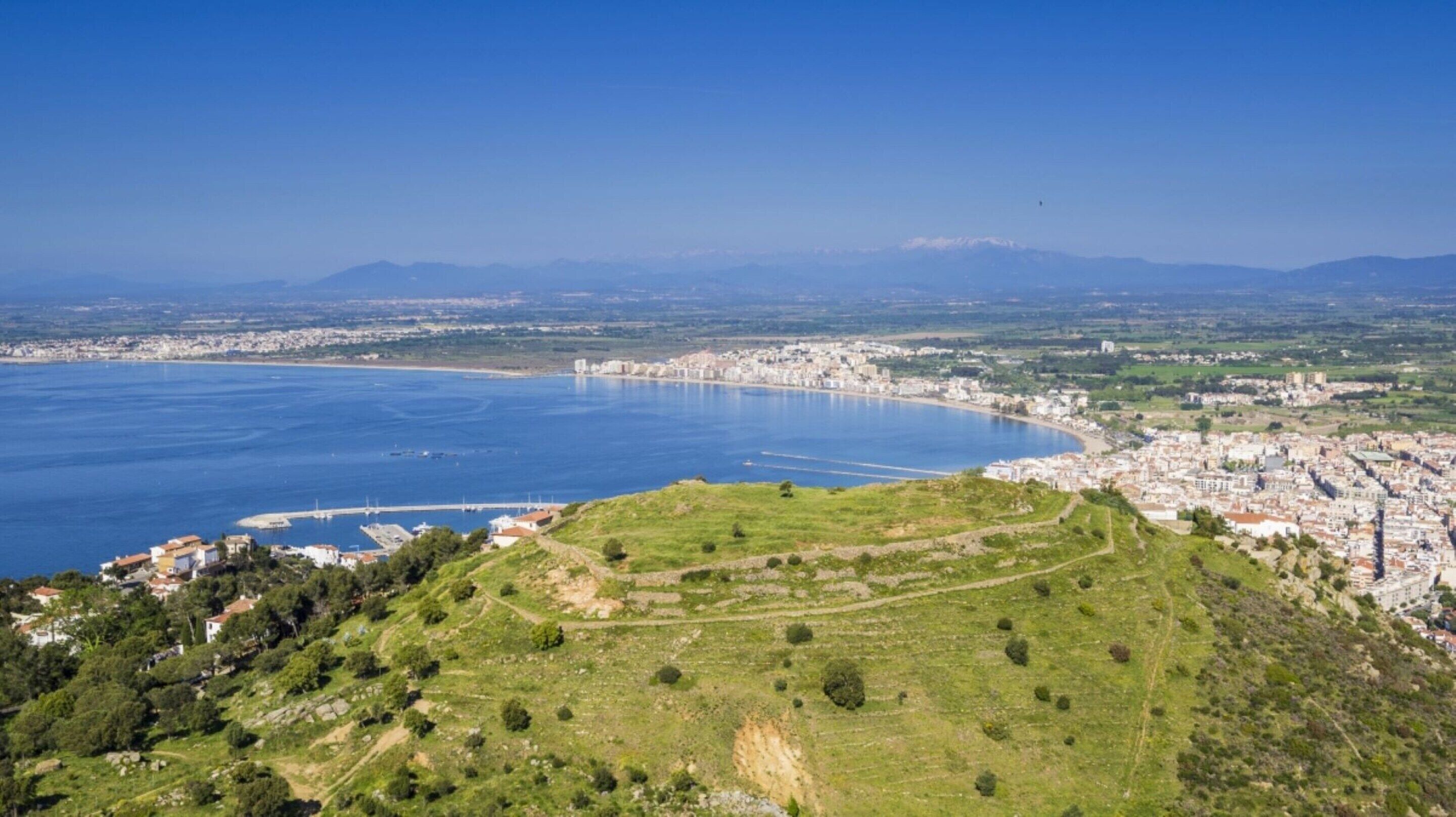 A coastal city with a large bay, a historic hill with ruins, and a dense urban area with buildings.