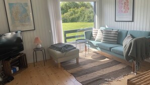 Ein Wohnzimmer mit Fernseher, Sofa, Couchtisch und Teppich.