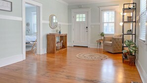 A spacious living room with hardwood floors, a beige sofa, a coffee table, and a bookshelf.