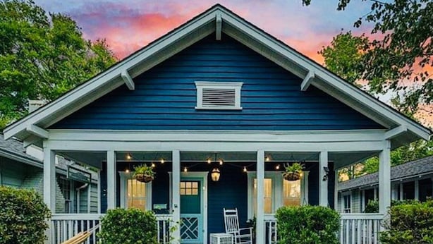 A two-story house with a porch, white railings, and a blue exterior.
