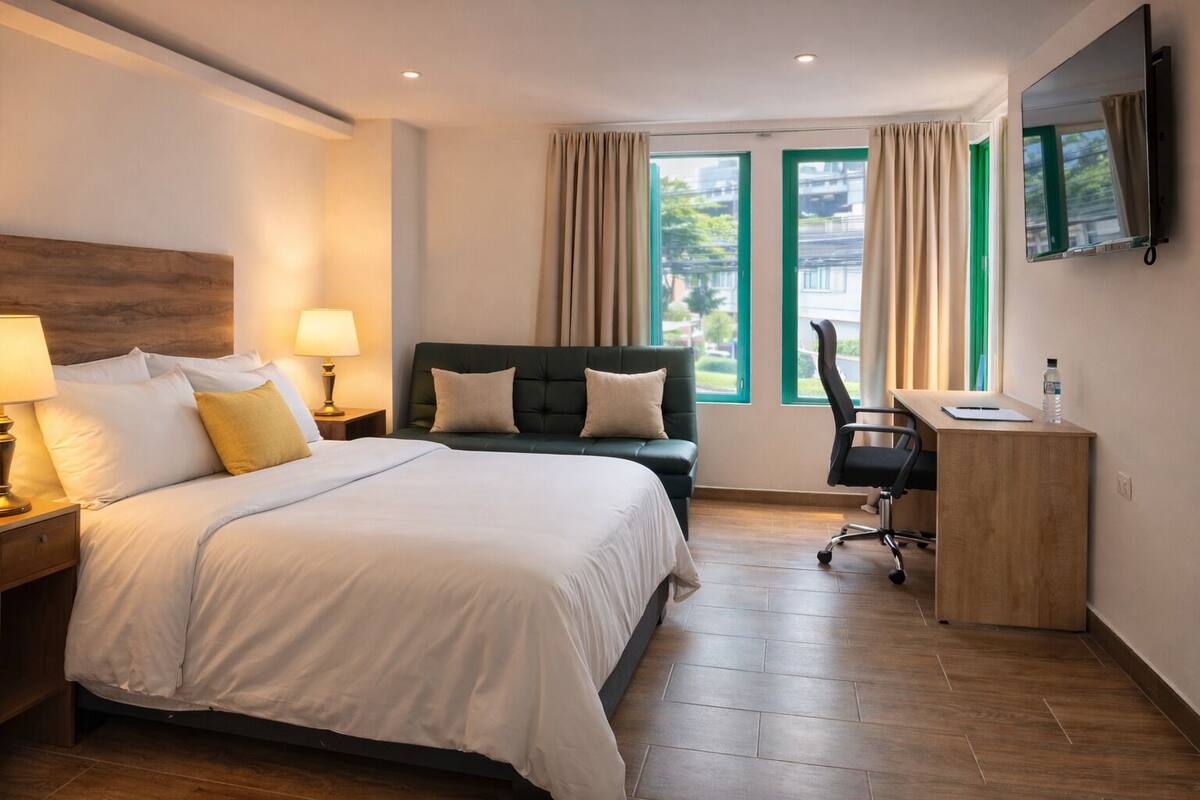 Una habitación de hotel con una cama, un escritorio, una silla y un televisor en la pared.