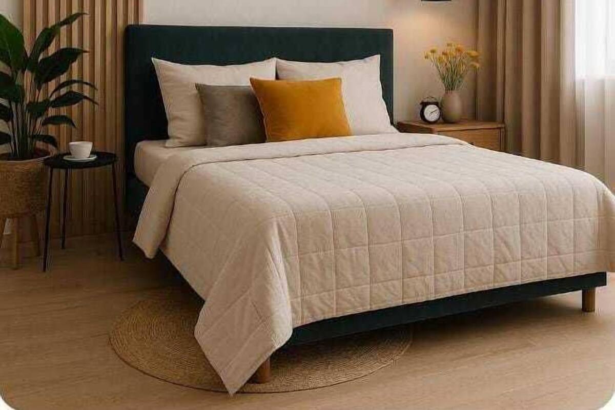 Un dormitorio con una cama, una mesita de noche, una planta en maceta y una lámpara de pared.
