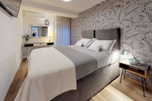 A modern bedroom with a large bed, a bedside table with a lamp, and a mirror.