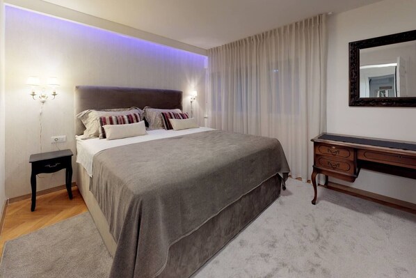 A bedroom with a bed, bedside tables, a desk, and a mirror.