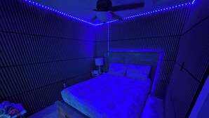 A bedroom with a bed, a ceiling fan, and a nightstand.
