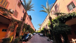 A narrow street lined with buildings, parked cars, and palm trees. - 10 minutes from the Majorelle garden Riad Beldi Chic An Authentic Stay”- Abritel (Marrakech)