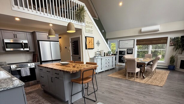A spacious kitchen with modern appliances, a wooden island, and a dining area with a large window.