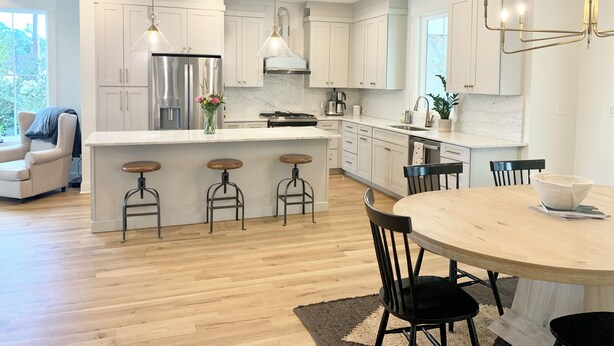 A modern kitchen with white cabinets, stainless steel appliances, and a central island with bar stools. - Newly built 4BR, close to Duke, ready for Duke Graduation! (Durham)