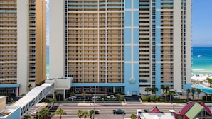A high-rise hotel with multiple balconies, a swimming pool, and a beach view. - Majestic 2212: Gulf-View Studio with Large Balcony | Free Fun! (Panama City Beach)