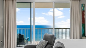 A hotel room with a large sliding glass door leading to a balcony with a view of the sea. - Majestic 2212: Gulf-View Studio with Large Balcony | Free Fun! (Panama City Beach)