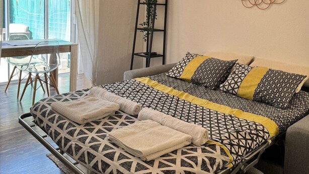 Een moderne slaapkamer met een bed, nachtkastje en een groot raam.