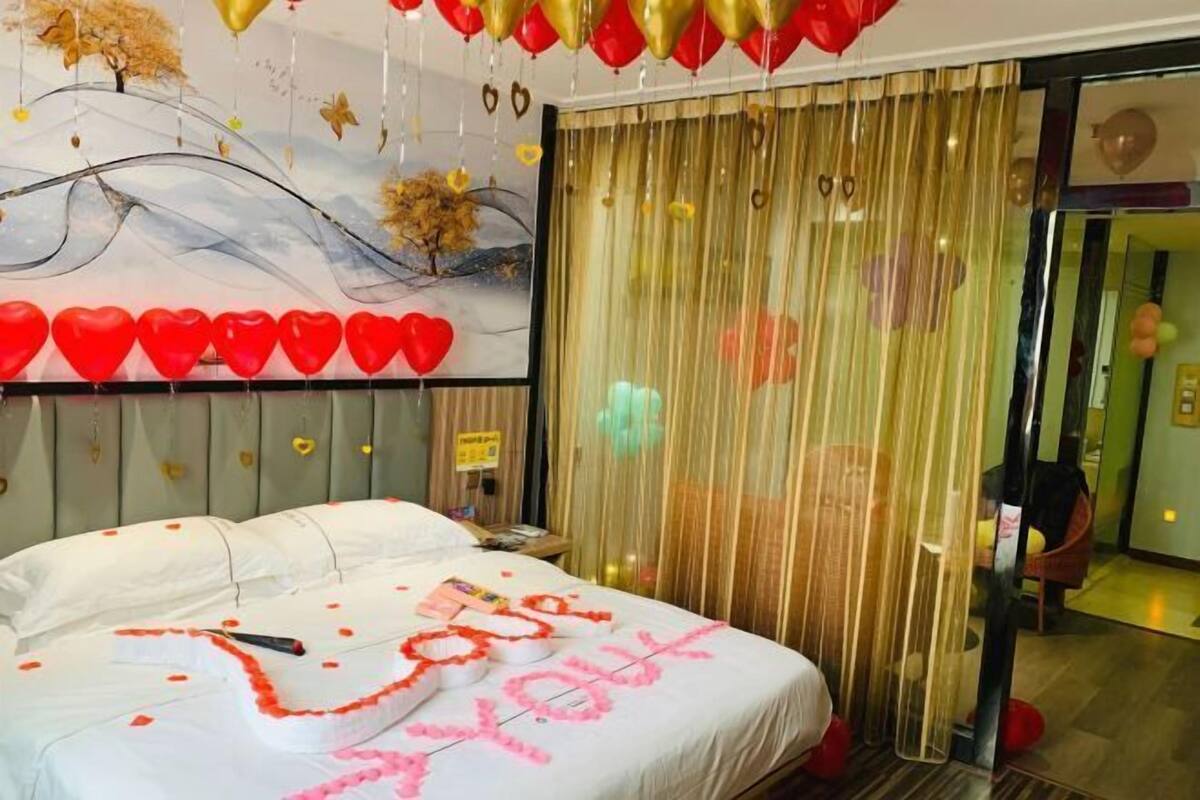 Une chambre d’hôtel avec un lit, un tableau au mur et un rideau.