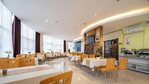 Uma ampla sala de jantar com várias mesas e cadeiras, janelas grandes e um balcão de buffet.