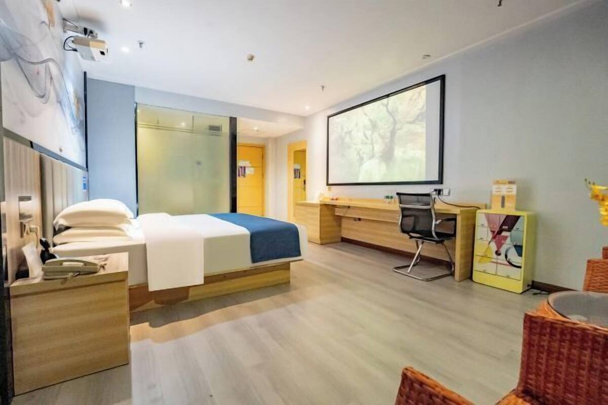 Une chambre d’hôtel moderne équipée d’un lit, d’un bureau et d’un grand écran.