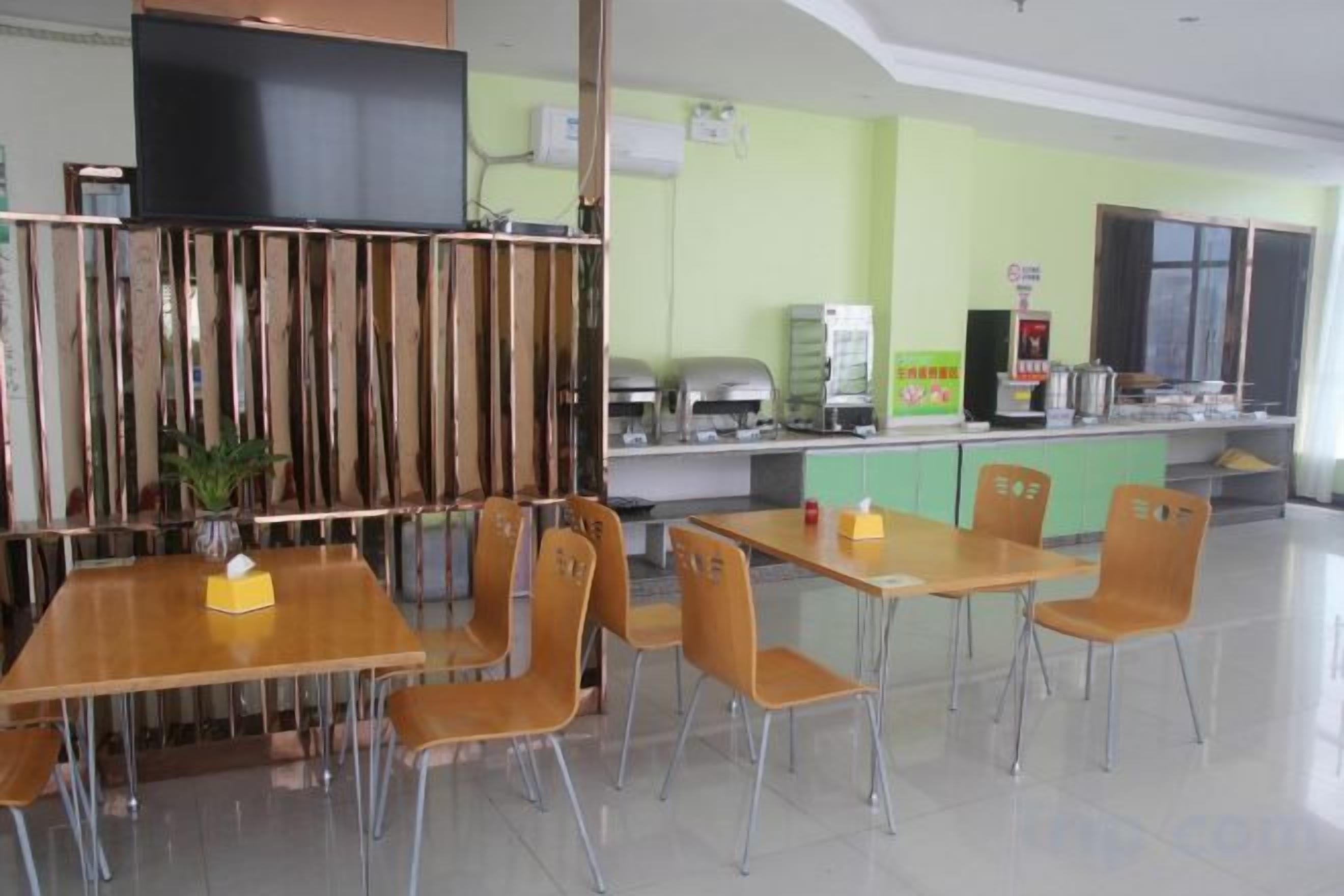 Un restaurant avec des tables et des chaises, un comptoir avec une machine à café et un téléviseur accroché au mur.