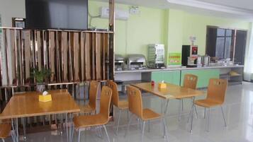 Un restaurant avec des tables et des chaises, un comptoir avec une machine à café et un téléviseur accroché au mur.